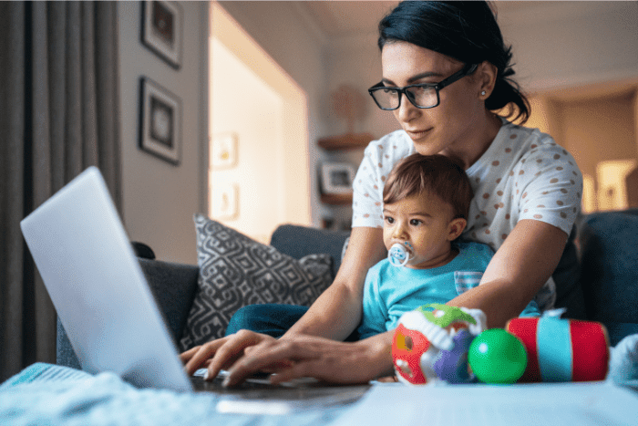 mom working from home on laptop with her baby on her lap