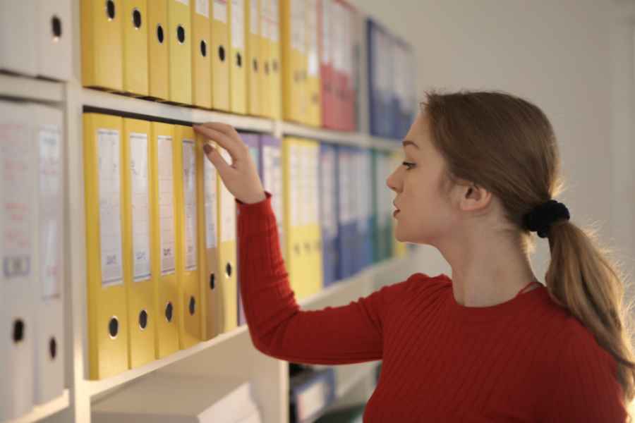 woman choosing from colorful binders on a shelf